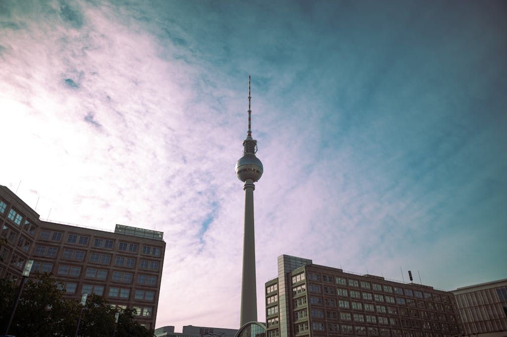 Berlin TV Tower against a vibrant blue sky viewed from below, capturing urban architecture.